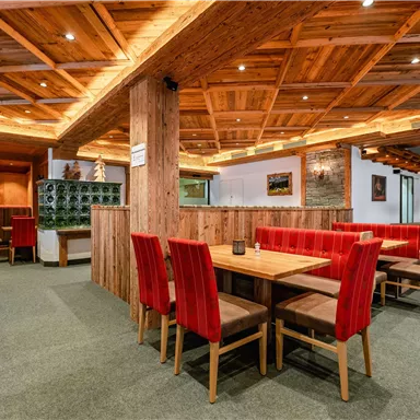 A cozy restaurant with wooden decor and red chairs. The atmosphere is inviting and warm.