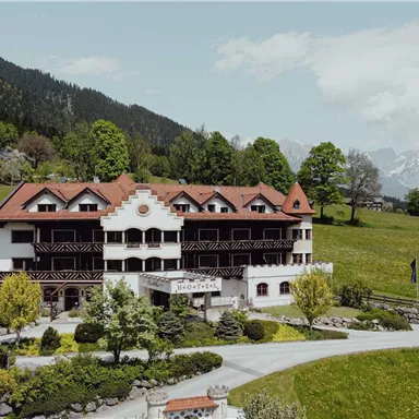 A charming hotel nestled in a picturesque mountain landscape. Surrounded by green meadows and trees, it exudes an inviting atmosphere.