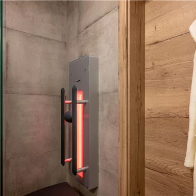 A modern shower area with a clear glass wall and an innovative shower control. A soft, white bathrobe hangs on the wall.