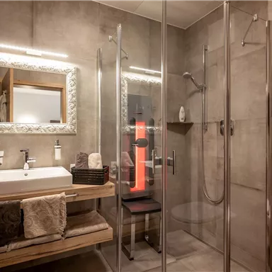 A modern bathroom with a glass-roofed shower and an elegant sink unit. The walls are in neutral tones and there are wooden details for a warm accent.