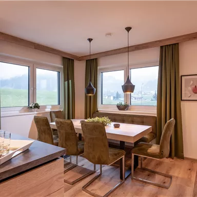 Modern dining room with a wooden table and stylish chairs. Large windows let in plenty of light and offer a view of the landscape.