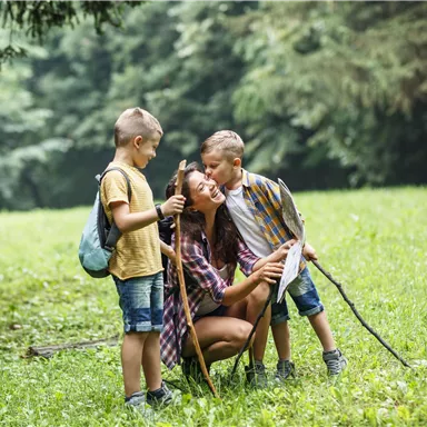 A mother spends time with her two sons in nature. They smile and enjoy their time together while hiking.