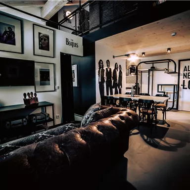 A modern living room with a comfortable couch and a large television. On the wall, there are pictures and an inspiring quote.