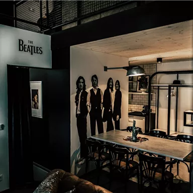 A stylish room with a Beatles wall decoration and a large table. The setting has a modern atmosphere with artworks on the walls.
