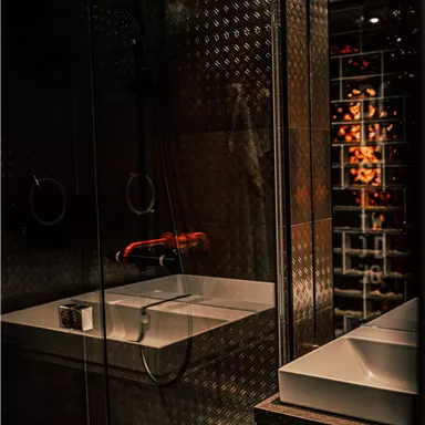 A modern bathroom with a glass shower and an elegant sink. The atmosphere is stylish and well-lit.