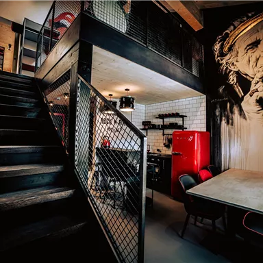 A modern interior design with a staircase and an open kitchen. A large artwork depicting a person hangs on the wall.