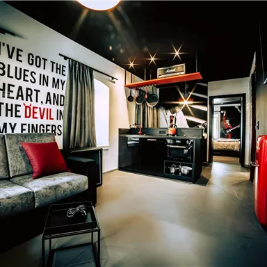 A modern room with a cozy sofa and a kitchenette. A striking lettering on the wall creates atmosphere.