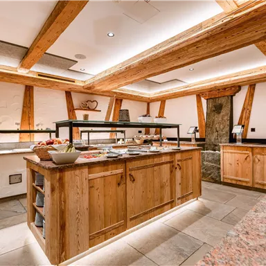 A modern kitchen with wooden shelves and a buffet. The atmosphere is warm and inviting.