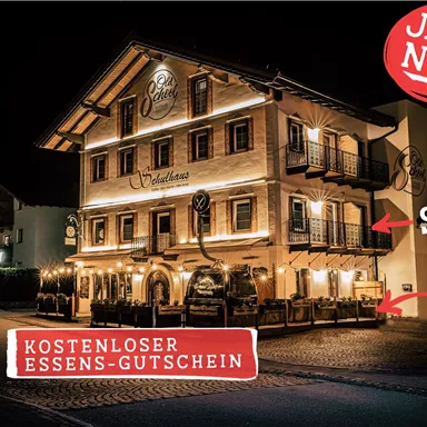 A charming hotel at night, brightly lit and inviting. A free meal voucher is offered.