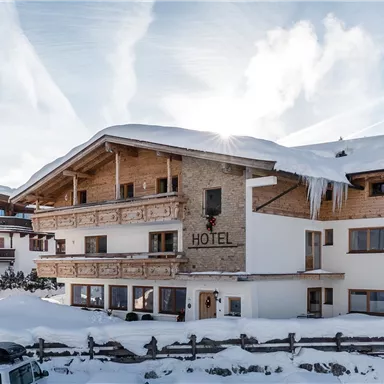 A charming hotel in the snow, surrounded by mountains. The landscape is wintry and inviting.