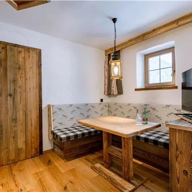 A cozy dining area with wood paneling and a modern TV unit. The room has a warm, inviting atmosphere with a window that lets in light.