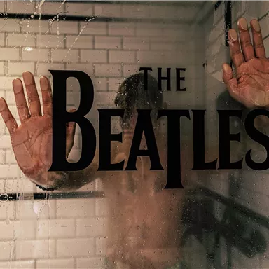 A blurred view of a person behind a shower wall with the inscription "The Beatles." The person's hands are pressed against the glass.