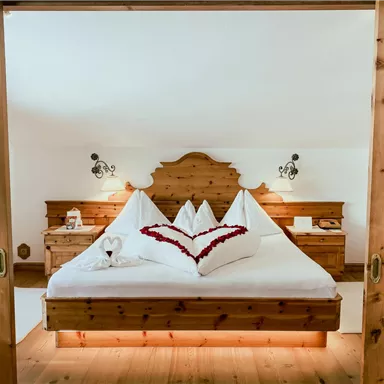 A cozy bedroom with a large bed and lovingly folded towels. The wooden furnishings create a warm atmosphere.