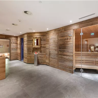 A modern wellness area with wooden walls and soft lighting. The sauna and reception areas are designed to be clear and inviting.