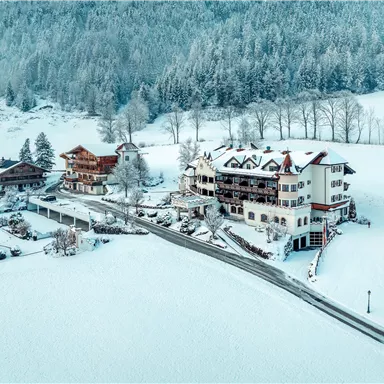 A picturesque winter landscape with snow-covered buildings. The surroundings are quiet and surrounded by mountains.
