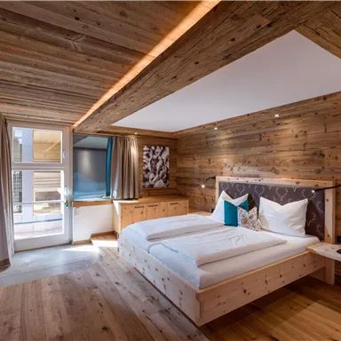 A modern bedroom with wood paneling and comfortable beds. Large windows provide plenty of light and an inviting view.
