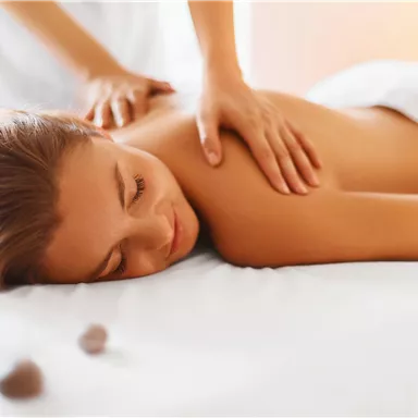 A relaxed woman is receiving a back massage in a wellness area. The atmosphere is calm and pleasant, perfect for relaxation.