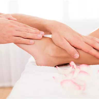 A relaxing foot massage is performed. Rose petals are placed on the table for a pleasant atmosphere.