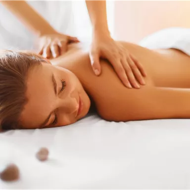 A relaxed woman is receiving a back massage. She is lying on a table and enjoying the treatment.