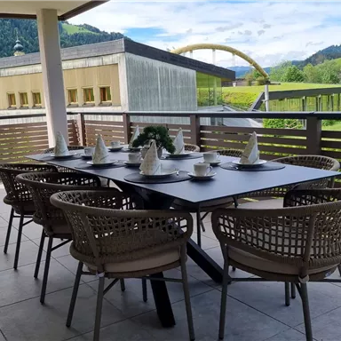 A cozy dining area on a terrace with a view of the mountains. The table is set for guests and offers a beautiful view of the landscape.