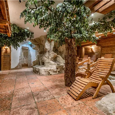 A relaxing wellness area with wooden furniture and artificial trees. Gentle lighting creates a calm atmosphere.