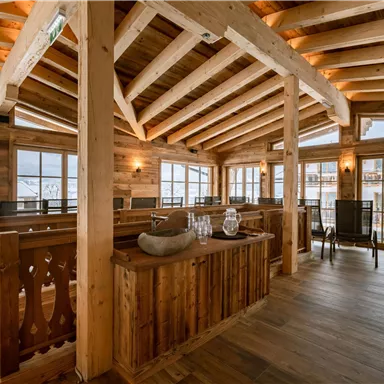 A cozy restaurant with wooden beams and large windows. The room has an inviting atmosphere with plenty of natural light.