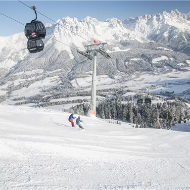 A snowy mountain landscape with skiers on the slopes. A cable car floats over the scene.