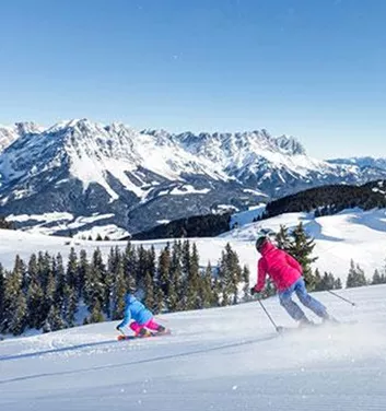 Ein schöner Skiort mit schneebedeckten Bergen und klar blauem Himmel. Zwei Skifahrer genießen die Piste in der Winterlandschaft.