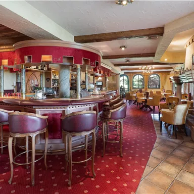 A cozy restaurant with an inviting bar and chairs. The space features warm colors and large windows that provide plenty of light.