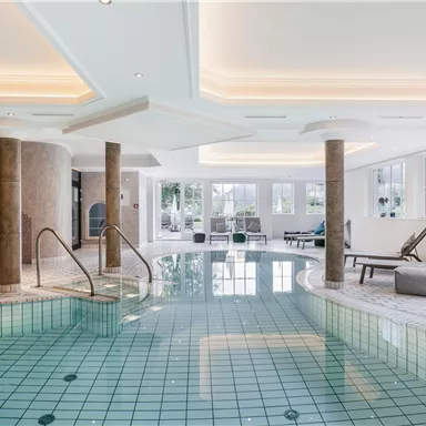 An elegant wellness area with a clear pool and large windows. Relaxing loungers invite you to linger.