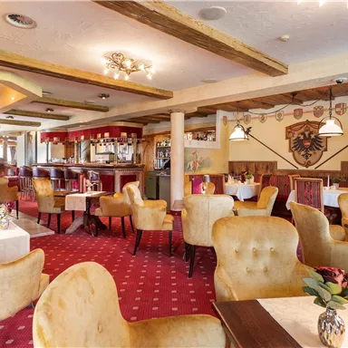 An elegant restaurant with comfortable, velvety chairs and warm lighting. The walls are adorned with traditional decorations and the floor is covered with red carpet.
