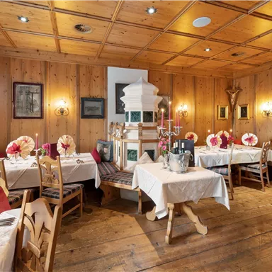 A cozy restaurant with wooden walls and beautifully decorated tables. Candles and cloth napkins create an inviting atmosphere.