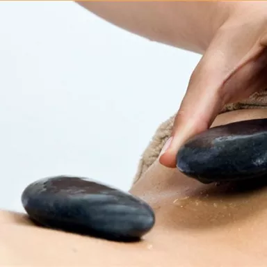 A person is receiving a healing massage with hot stones. The relaxing environment and the careful application promote well-being.