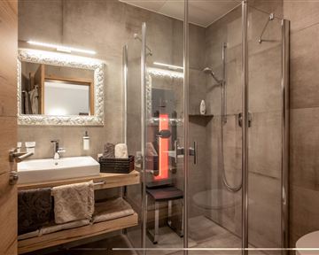 A modern bathroom with a glass shower and light wood details. The mirror and the sink faucet create a stylish atmosphere.