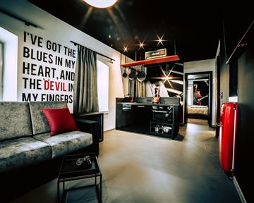 Ein modernes Zimmer mit einem Sofa und einer kleinen Küchenzeile. An der Wand steht ein kreativer Spruch in großen Buchstaben.