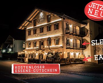 A charming hotel at night, brightly lit and inviting. A free meal voucher is offered.