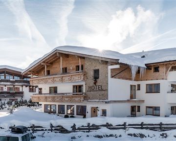 A charming hotel in the snow, surrounded by mountains. The landscape is wintry and inviting.