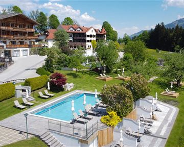 Ein schöner Außenbereich mit einem Pool und Liegen. Im Hintergrund sind malerische Berge und grüne Wiesen zu sehen.