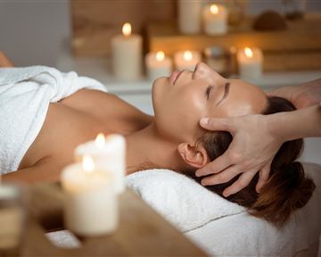 A woman is receiving a relaxing massage in a calm spa. Surrounded by candles, the atmosphere radiates peace and relaxation.
