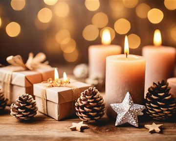 Eine festliche Dekoration mit Kerzen, Geschenken und Tannenzapfen. Im Hintergrund funkeln weiche Lichter.