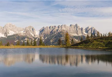Eine malerische Berglandschaft mit schneebedeckten Gipfeln und einem ruhigen See im Vordergrund. Die Natur strahlt Frieden und Schönheit aus.