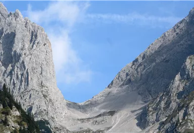 Eine majestätische Berglandschaft mit hohen Felsen und einem klaren blauen Himmel. Die tiefen Täler und steilen Hänge verleihen der Szenerie eine beeindruckende Schönheit.