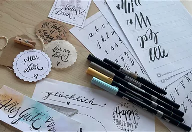 Eine Sammlung von handschriftlichen Notizen, Stiften und Bastelmaterialien. Die Oberflächen sind kreativ gestaltet mit verschiedenen Schriftarten und Farbakzenten.