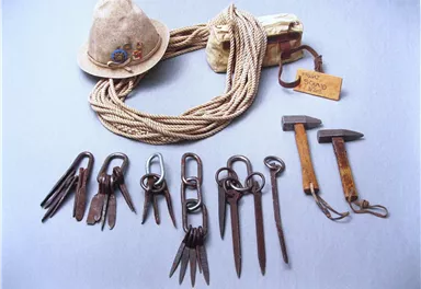 Ein Hutmacher-Set mit verschiedenen Werkzeugen, darunter eine Hutform, Scheren und Hämmer. Dazu gehört auch ein Seil und eine kleine Tasche.