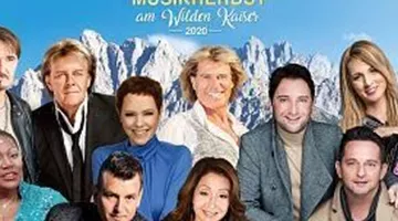 Eine Gruppe von Musikern steht vor einer beeindruckenden Bergkulisse. Das Bild zeigt verschiedene Künstler, die an einem Musikfestival teilnehmen.