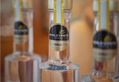 Eine Reihe von Flaschen, die mit einer Goldmedaille für den World Spirits Award 2023 ausgezeichnet sind. Die Flaschen sind klar und haben einen eleganten Look.