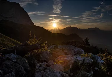 Ein beeindruckender Sonnenaufgang über den Bergen. Die goldenen Strahlen beleuchten die Felsen und die sanfte Landschaft.