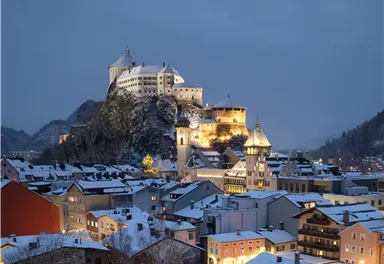 A picturesque town in winter, covered in snow. In the background stands an impressive castle, shining in soft light.