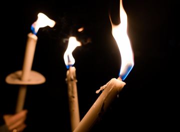 Drei brennende Kerzen in der Dunkelheit. Die Flammen tanzen sanft und erzeugen eine warme Atmosphäre.