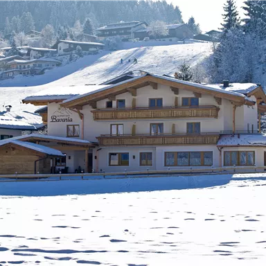 Ein malerisches Chalet im Winter, umgeben von Schnee und Bergen. Das Gebäude hat Holzverkleidungen und große Fenster.